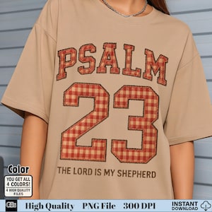Puede incluir: Una camiseta color beige con el texto "PSALM 23" en un diseño a cuadros rojos y beige. Debajo, el texto dice "THE LORD IS MY SHEPHERD". La camiseta tiene mangas cortas y cuello redondo.