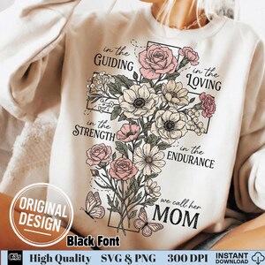Close up of a woman wearing a cream sweatshirt with a Christian floral cross and the quote we call her mom in black font.