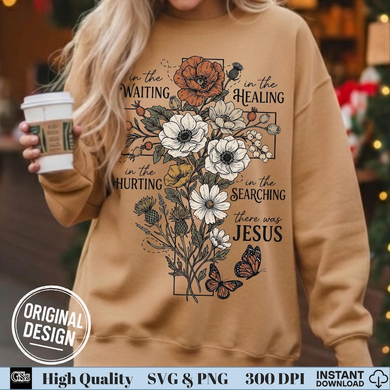 Woman holding a coffee cup wearing a tan sweatshirt with a beautiful retro floral cross faith design.