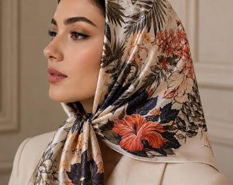 May include: A square silk headscarf featuring a botanical print with large orange hibiscus flowers, dark green foliage, and cream-colored floral accents on a light cream background, tied securely under the chin with a smooth, satin-like finish.