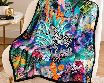 May include: A square silk scarf featuring a vibrant, multi-colored jungle scene with a central black and white zebra. The design includes detailed illustrations of orange cacti, blue agave plants, and various colorful flowers, all framed by a solid black border.