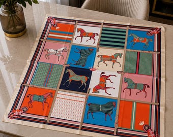 May include: A square silk scarf featuring a grid pattern of twelve panels. Each panel displays illustrations of horses in various colors, including orange, blue, pink, and green, alongside geometric stripes, plaid motifs, and small crown icons.