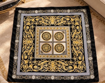 May include: A square scarf featuring a black background with an intricate gold and white baroque pattern. The design includes a central grid of four circular medallions, surrounded by ornate scrolling acanthus leaves and a Greek key border.