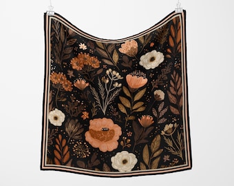May include: Square scarf with a floral pattern. The scarf features a black background with a repeating pattern of flowers and leaves in shades of peach, brown, and white. The border has a black and peach stripe.