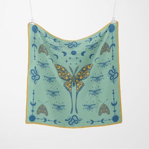 May include: A square scarf with a light green background and a repeating pattern of moths, snakes, moons, and stars. The central moth is large and detailed, with yellow and blue patterns. The border is a darker blue with yellow trim.
