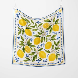 May include: A square white scarf with a lemon and floral design. The scarf features yellow lemons, green leaves, and white flowers. The border is blue and yellow with decorative patterns.