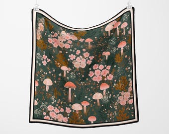 Puede incluir: Pañuelo cuadrado con fondo verde oscuro con un estampado de flores rosas y setas con sombrero rojo. El pañuelo tiene un borde blanco y negro y está colgado de una pinza.