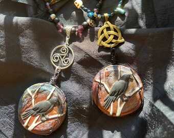 May include: Two necklaces with black beads, silver and gold accents, and a Celtic knot pendant. The necklaces feature a raven on a branch pendant and a skull pendant.