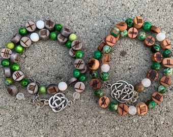 May include: Two green and brown beaded bracelets with wooden beads featuring carved symbols and silver Celtic knot clasps.