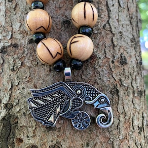 May include: A silver pendant necklace with a detailed design of a wolf's head. The pendant is attached to a wooden bead necklace with black beads.