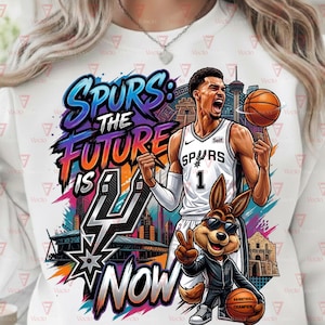 Könnte beinhalten: Weißes Sweatshirt mit einem Grafikdesign. Das Design zeigt einen Basketballspieler im Spurs-Trikot, einen Cartoon-Kojoten und den Text "Spurs: The Future is Now". Das Design umfasst Stadtlandschaften und einen Basketball.