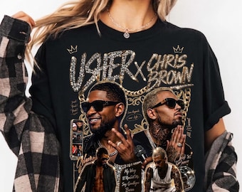 May include: Black t-shirt featuring a graphic design with the text "USHER X CHRIS BROWN" in a sparkling font. The design includes images of Usher and Chris Brown, with additional text and graphics. The shirt has a crew neck.