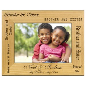 May include: A light-colored wooden picture frame with the words "Brother & Sister" and "Brother and Sister" engraved on it. The frame holds a photo of a smiling brother and sister. The names "Noel & Ivelisse" are also engraved on the frame.