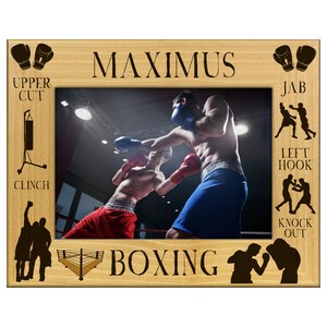 May include: Wooden picture frame with the name "MAXIMUS" at the top and the word "BOXING" at the bottom. The frame contains a photo of two boxers in a ring, wearing gloves and shorts. Boxing-related illustrations are on the frame.