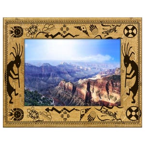 May include: A rectangular wooden picture frame with a landscape image of a canyon. The frame has a light brown finish with black tribal designs, including figures, turtles, and geometric shapes. The image shows a blue sky.