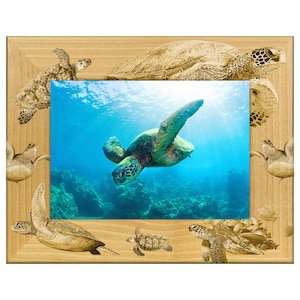 May include: Wooden picture frame featuring a vibrant underwater scene with a green sea turtle swimming in blue water. The frame has a light brown finish with engraved sea turtles around the edges. A perfect addition to any home decor.