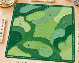 May include: A square green game mat featuring an abstract oil painting of a golf course with miniature figures of golfers. The border includes text reading DRAGONS, RAMS, and JOKERS. White mahjong tiles with red and green symbols surround the mat.