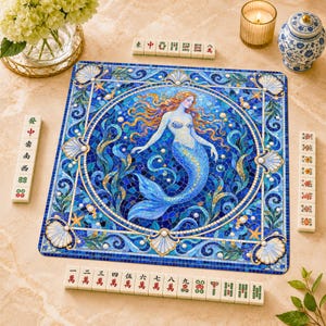 Könnte beinhalten: Eine quadratische Spielmatte mit einer Mosaik-Illustration einer Meerjungfrau mit fließendem orangefarbenem Haar und blauem Schwanz, umgeben von Muscheln und Seesternen. Die Matte hat einen blauen Rahmen und ist von Mahjong-Steinen umgeben.