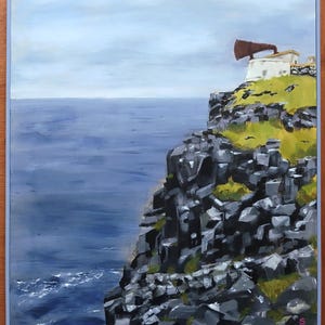 Puede incluir: Pintura al óleo de un paisaje costero con un edificio blanco y una gran estructura marrón en forma de cuerno en la cima de un acantilado. El acantilado está compuesto por rocas de color gris oscuro, y el mar se extiende bajo un cielo nublado. El cuadro está enmarcado.