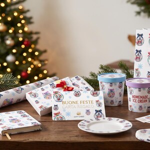 Può includere: Una collezione di articoli natalizi con un motivo ripetuto di animali dei cartoni animati in ornamenti, tra cui una borsa regalo, carta da regalo, un taccuino, contenitori per gelato, una carta regalo BUONE FESTE e una calza natalizia.
