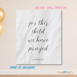 Op de afbeelding: Een wit wandtapijt van 173 cm bij 203 cm met de zwarte tekst "for this child we have prayed" in een cursief lettertype, gevolgd door de vermelding "1 SAMUEL 1:27" in een eenvoudig schreefloos lettertype in het midden van de stof.