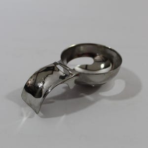 May include: A stainless steel ice cream scoop with a curved handle and a circular bowl. The scoop has a trigger mechanism for easy release and is designed for scooping and serving ice cream. The handle is curved for a comfortable grip.