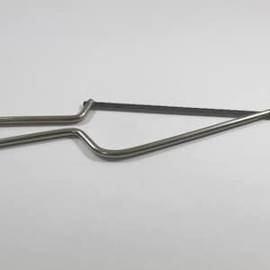 May include: A small, silver-colored coping saw with a black blade. The saw has a curved handle and a triangular frame, designed for intricate cuts in woodworking or crafts. The blade is thin and toothed.