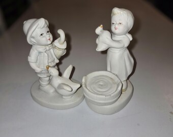 Figuritas de porcelana blanca bizcochada de los años 60 que representan a un niño y una niña con patos.