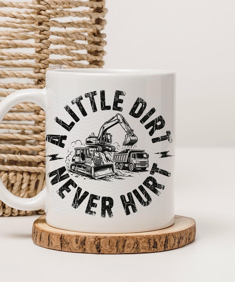 May include: White ceramic mug with a black and white graphic of construction vehicles, including an excavator, bulldozer, and dump truck. The text "A LITTLE DIRT NEVER HURT" is printed around the vehicles. The mug sits on a wooden coaster.