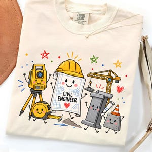 Puede incluir: Una camiseta color crema con un gráfico colorido de herramientas y equipos de construcción estilo caricatura. El diseño incluye un casco amarillo, un plano con el texto CIVIL ENGINEER, una grúa, una cinta métrica y un teodolito.