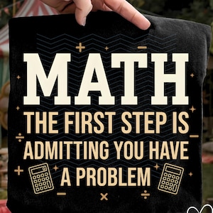 May include: Black t-shirt with the word "MATH" in large white letters. Below, the text reads "THE FIRST STEP IS ADMITTING YOU HAVE A PROBLEM" in a tan colour. The design includes calculator graphics and mathematical symbols.