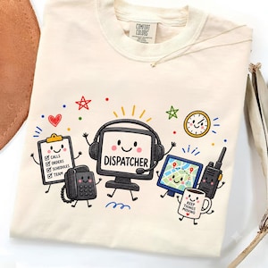 Könnte beinhalten: Ein cremefarbenes T-Shirt mit einer bunten Grafik aus Bürogeräten im Cartoon-Stil, darunter ein Computermonitor mit Kopfhörern und der Aufschrift DISPATCHER, ein Klemmbrett, ein Telefon, eine Karte, ein Funkgerät und eine Tasse mit der Aufschrift KEEP THINGS MOVING.