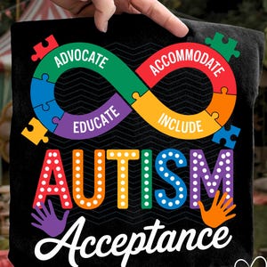 May include: Black t-shirt with a colorful graphic promoting autism acceptance. The design features an infinity symbol made of puzzle pieces, the word "AUTISM" in bright letters, and the word "Acceptance" in white.