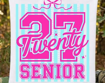 May include: White tote bag with a pink and light blue design. The design includes the number 27, the word "Twenty", and the word "Senior" in a pink, bold font. Light blue vertical stripes are in the background, and a pink bow is at the top.