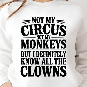 May include: White sweatshirt featuring the black text: "NOT MY CIRCUS NOT MY MONKEYS BUT I DEFINITELY KNOW ALL THE CLOWNS". The text is stacked, with each line centered, creating a bold statement.