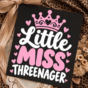 May include: A black rectangular sign featuring a pink crown graphic at the top and the white and pink text "Little MISS THREENAGER" in the center. The design is surrounded by small pink heart icons arranged across the black background surface.