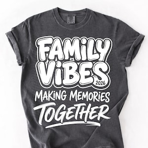 May include: Dark gray t-shirt with the words "FAMILY VIBES 2026 MAKING MEMORIES TOGETHER" in white, bold, bubble letters. The shirt has rolled-up sleeves and a crew neck.
