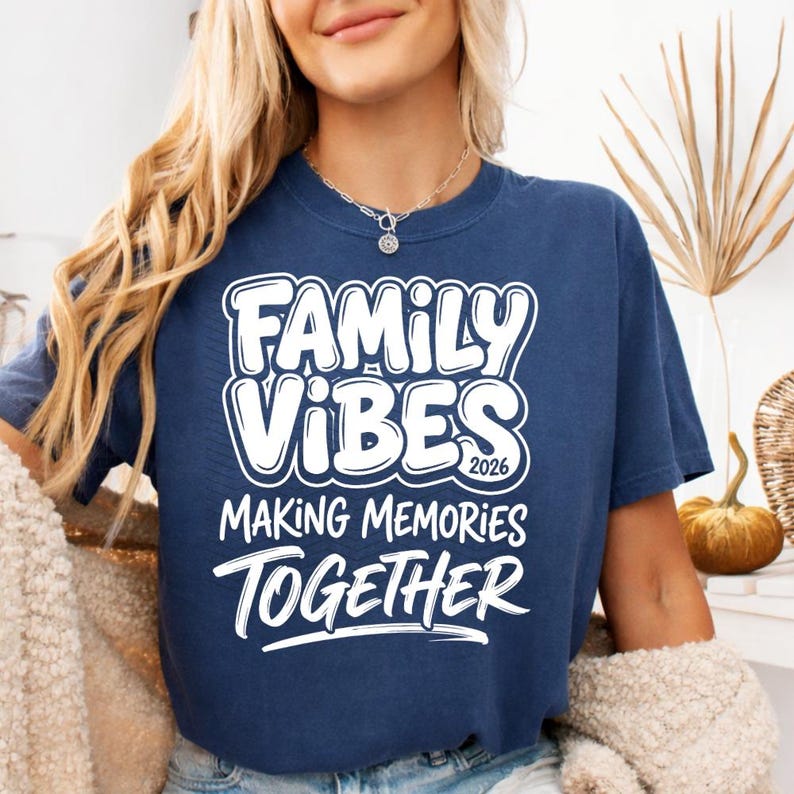 May include: Navy blue t-shirt with the words "FAMILY VIBES 2026 MAKING MEMORIES TOGETHER" in white, bold, bubble letters. The shirt is a casual style, suitable for family gatherings or events.