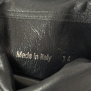 Peut inclure: Gros plan sur du cuir noir avec l'inscription "Made in Italy" et le chiffre "36" en relief. Le cuir pr&eacute;sente un aspect textur&eacute; et un l&eacute;ger &eacute;clat. Le chiffre 36 indique probablement une pointure.