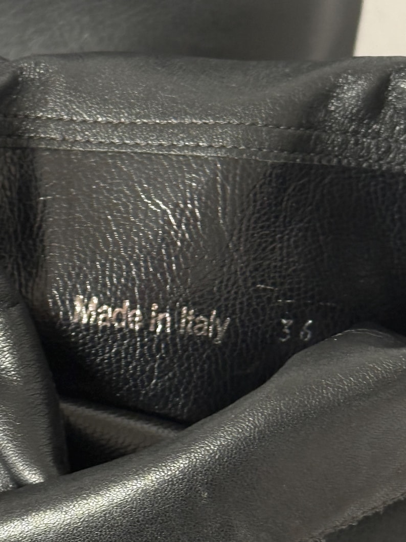 Peut inclure: Gros plan sur du cuir noir avec l'inscription "Made in Italy" et le chiffre "36" en relief. Le cuir pr&eacute;sente un aspect textur&eacute; et un l&eacute;ger &eacute;clat. Le chiffre 36 indique probablement une pointure.