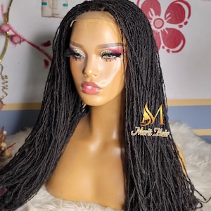 May include: A black micro-braid wig styled on a mannequin head. The wig features a lace front and is styled with long, individual braids. The mannequin has makeup applied, including eyeshadow and lipstick. The wig is displayed on a white surface.