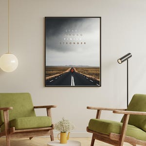 K&ouml;nnte beinhalten: Gerahmter Kunstdruck mit einer langen, geraden Stra&szlig;e unter einem bew&ouml;lkten Himmel. Der Text "START STRONG FINISH STRONGER" ist &uuml;ber der Stra&szlig;e zu sehen. Das Bild befindet sich in einem Raum mit gr&uuml;nen Sesseln und einem kleinen Tisch.
