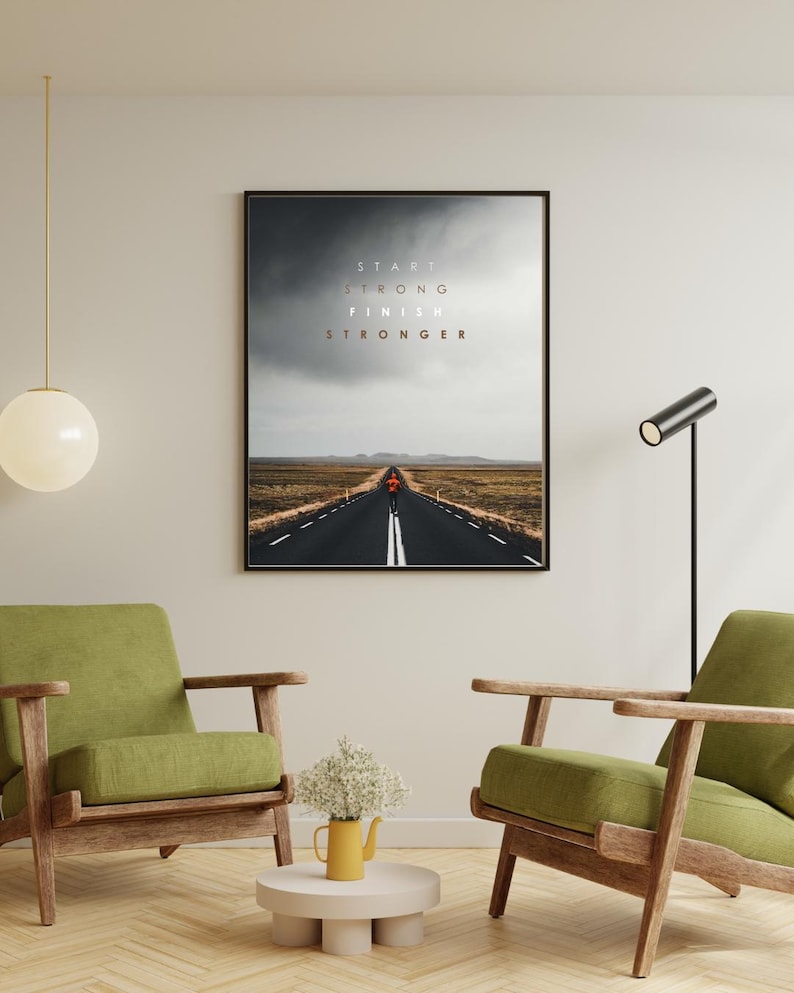 K&ouml;nnte beinhalten: Gerahmter Kunstdruck mit einer langen, geraden Stra&szlig;e unter einem bew&ouml;lkten Himmel. Der Text "START STRONG FINISH STRONGER" ist &uuml;ber der Stra&szlig;e zu sehen. Das Bild befindet sich in einem Raum mit gr&uuml;nen Sesseln und einem kleinen Tisch.