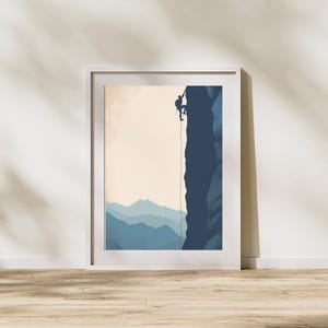 Könnte beinhalten: Gerahmter Kunstdruck mit einem Bergsteiger, der eine dunkelblaue Felswand erklimmt. Das Kunstwerk hat einen minimalistischen Stil mit einer Palette aus Blau-, Beige- und Weißtönen. Der Hintergrund zeigt eine Reihe blauer Bergketten.
