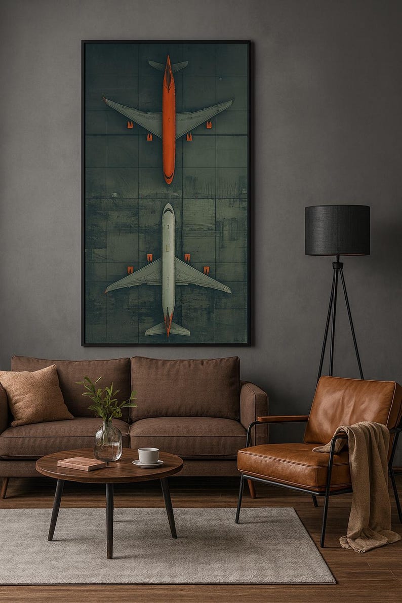 Puede incluir: Una impresi&oacute;n enmarcada que presenta dos aviones, uno naranja y otro blanco, en una pista verde. La obra de arte se exhibe en una sala de estar con un sof&aacute; marr&oacute;n, una silla de cuero y una l&aacute;mpara de pie negra. La est&eacute;tica general es moderna y minimalista.