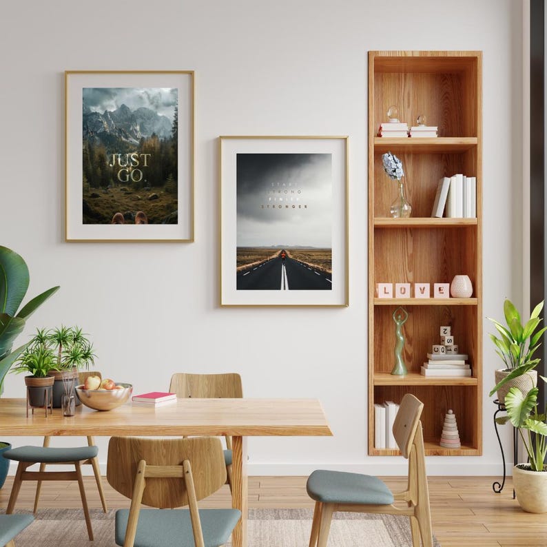 K&ouml;nnte beinhalten: Zwei gerahmte Kunstdrucke mit goldenen Rahmen an einer wei&szlig;en Wand. Einer zeigt eine Berglandschaft mit dem Text "JUST GO". Der andere zeigt eine Stra&szlig;e zum Horizont mit dem Text "STOP FEELING START DOING FEEL STRONGER."