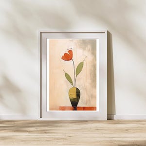 May include: Abstract art print featuring a red flower in a yellow and black vase. The artwork has a textured, painted appearance and is set against a neutral background. The framed print is displayed on a wooden floor.