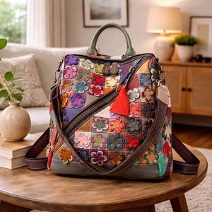 May include: A colorful patchwork leather backpack with a floral design. The bag features a variety of colors, including red, purple, green, and orange, with a red tassel and a green handle. The bag has adjustable straps and a zipper closure.