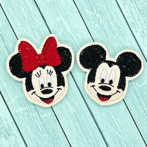 May include: Two embroidered felt patches of Mickey Mouse and Minnie Mouse. Mickey Mouse is black with white eyes and a red mouth. Minnie Mouse is black with white eyes and a red mouth and a red bow.