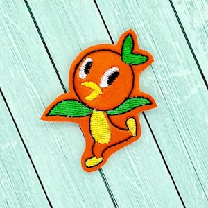 May include: Orange bird character with green leaves and a yellow beak, embroidered on a fabric patch.